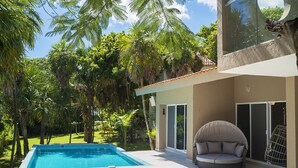 A modern outdoor pool area with a circular seating area and a hanging chair, surrounded by lush greenery. - Casa Matuk 3 Refurnished Home Excelent for Family Retreat (Playa del Carmen)