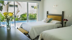 A hotel room with two beds, a dining table, and a view of a pool and greenery outside. - Casa Matuk 3 Refurnished Home Excelent for Family Retreat (Playa del Carmen)