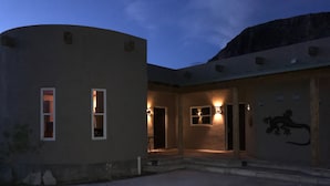 Een gebouw met een gebogen gevel, een kleine ingang met treden, en een wandlamp.