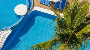 A pool area with blue lounge chairs and white umbrellas.