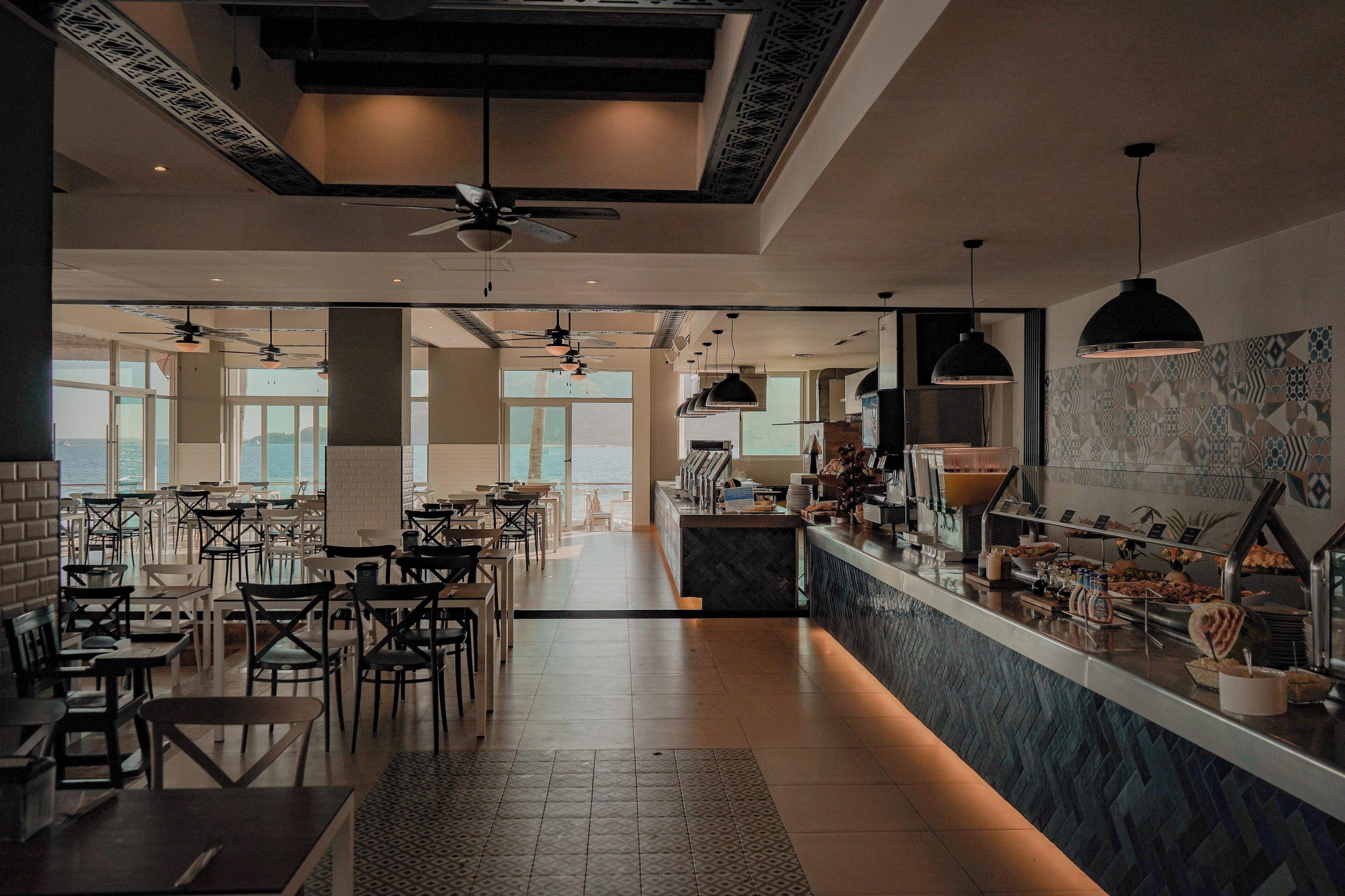Un restaurante moderno con bufé, techos altos y grandes ventanales.