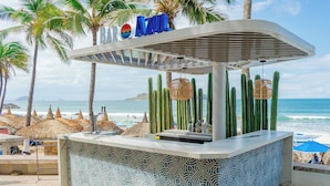 A beach bar named "BAR AZUL" with a patterned tile design, surrounded by palm trees and cacti, overlooking the ocean. - Oceano Palace Beach Resort (Mazatlán)
