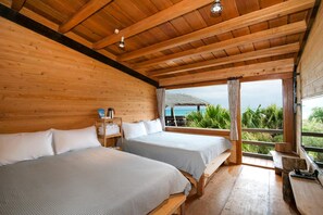 Uma cabana de madeira com duas camas, um banco de madeira e vista para o oceano.