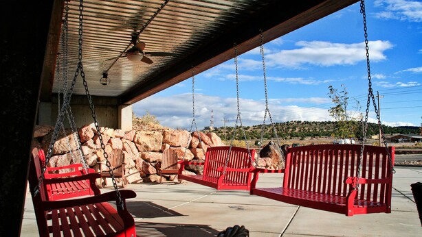 A covered outdoor area with red benches and a ceiling fan. - Iron Springs Adventure Resort & RV Park (Cedar City)