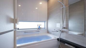 A modern bathroom with a freestanding bathtub, a large mirror, and a shower area.