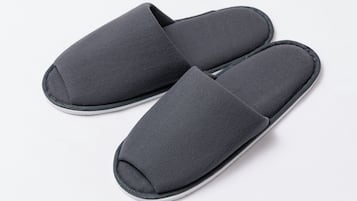 A pair of dark gray, fabric slippers with a white sole.