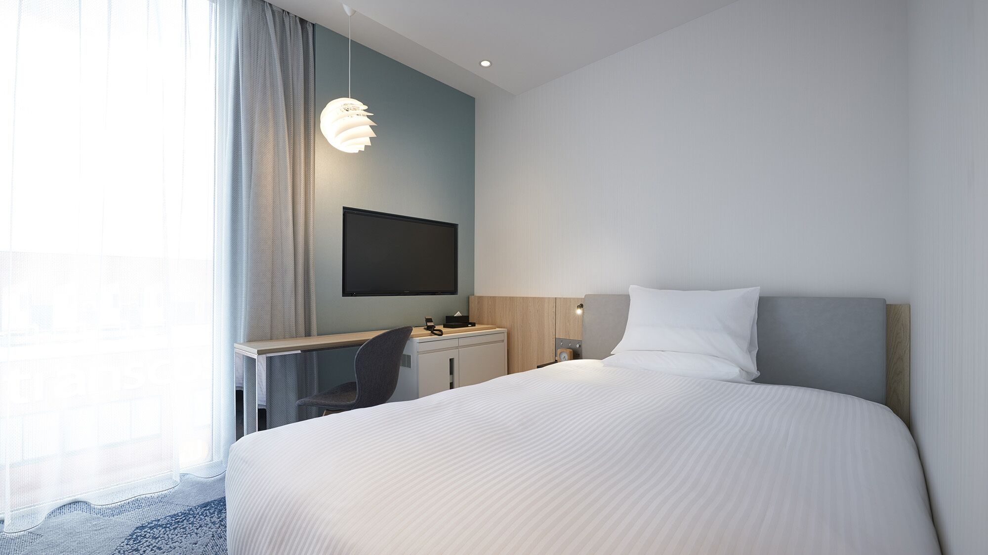 Ein modernes Hotelzimmer mit Bett, Schreibtisch und Fernseher.
