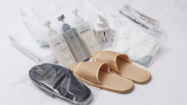 A collection of toiletries including body wash, shampoo, and hand soap, along with a pair of slippers and a small bag, likely containing additional items.