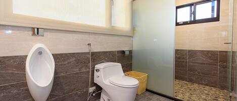 Un baño moderno con orinal, inodoro y zona de ducha.