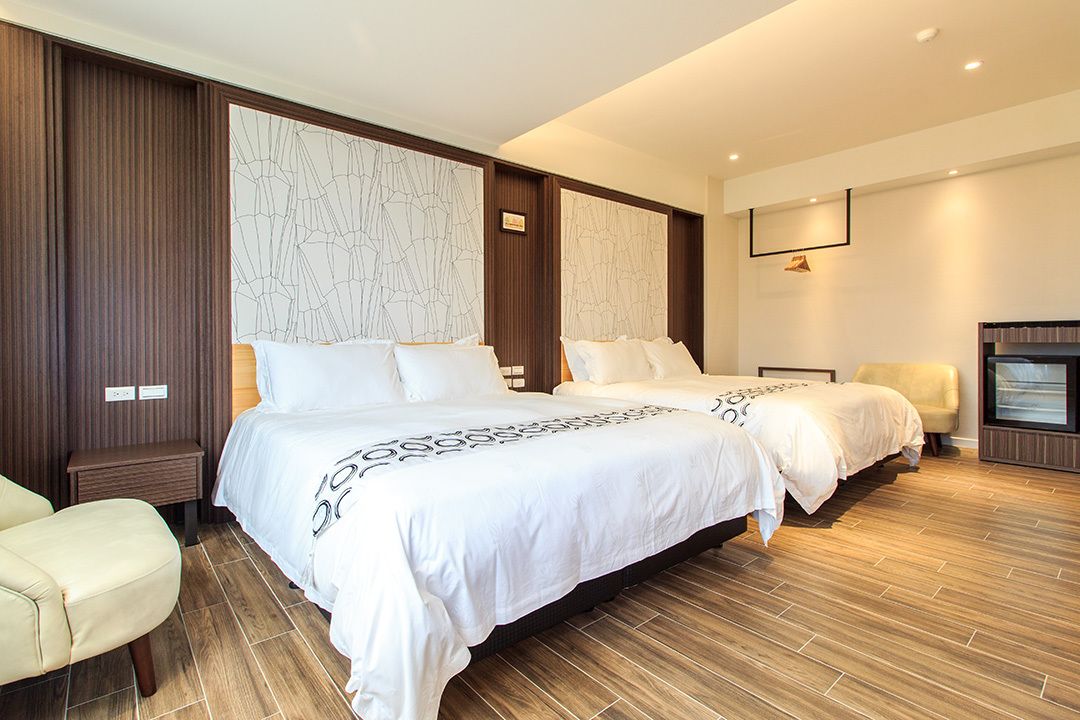 Ein modernes Hotelzimmer mit zwei Betten, einer Sitzecke und einem Fernseher.