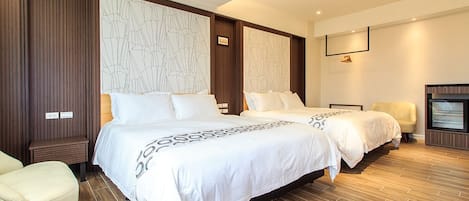 A modern hotel room with two beds, a seating area, and a television.
