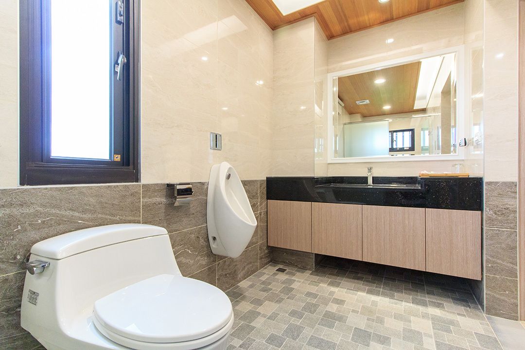 Ein modernes Badezimmer mit Toilette, Urinal und Waschbecken.