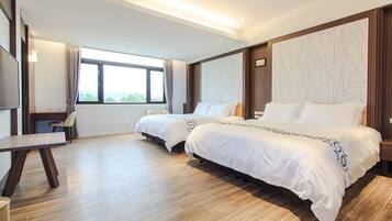 A hotel room with two beds, a desk, and a large window.