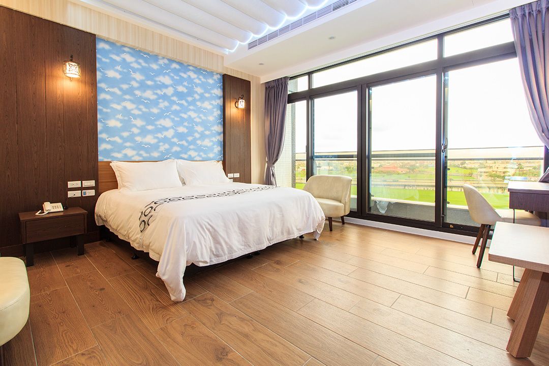 Ein Hotelzimmer mit einem großen Bett, einem Schreibtisch und Blick auf die Landschaft.