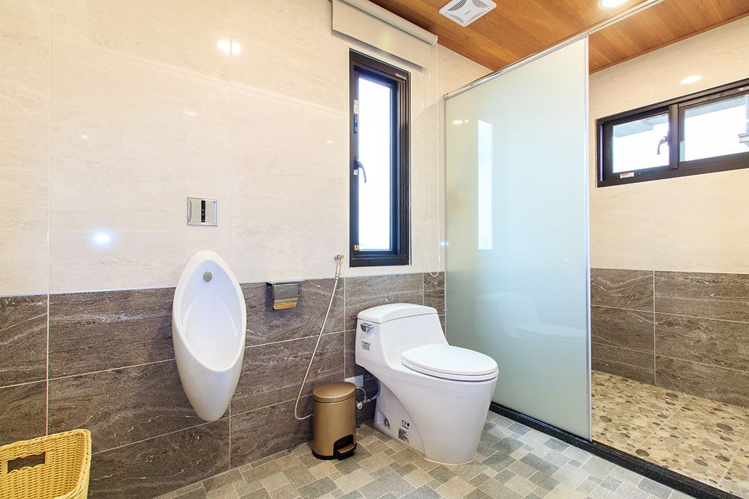 A modern bathroom with a urinal, toilet, and a glass shower enclosure.