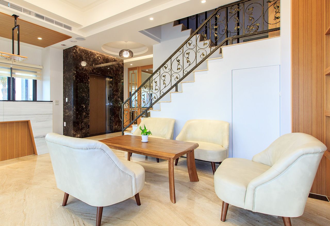 A modern interior with a marble wall, a wooden staircase, and a seating area with two chairs and a table.