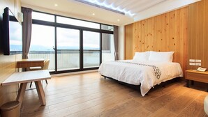 A modern hotel room with a large bed, a desk, and a view of the city through large windows. - Urban Oasis Inn (Luodong)