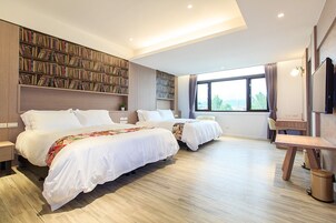 Una habitación de hotel moderna con dos camas, una amplia estantería, un escritorio y una ventana con vistas.