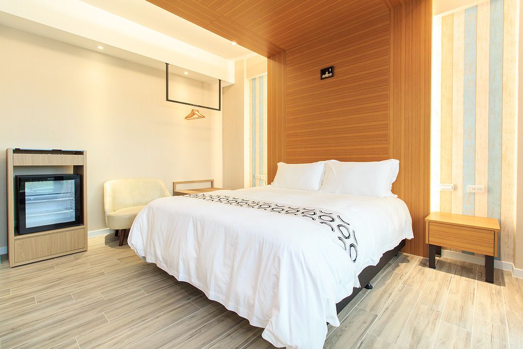 A modern bedroom with a large bed, a bedside table, a wardrobe, and a built-in TV.