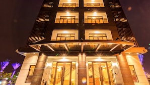 A multi-story hotel with a modern architectural design, featuring a prominent entrance with glass doors and a covered walkway. - Urban Oasis Inn (Luodong)