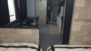 Una habitación con cama, escritorio y kitchenette.