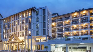 A multi-story hotel with a modern design, featuring balconies on each floor and a covered entrance area. - Monkham Village Hatyai (Hat Yai)