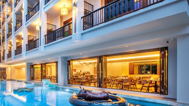 A multi-story hotel with a swimming pool, outdoor seating, and a restaurant/lounge area. - Monkham Village Hatyai (Hat Yai)