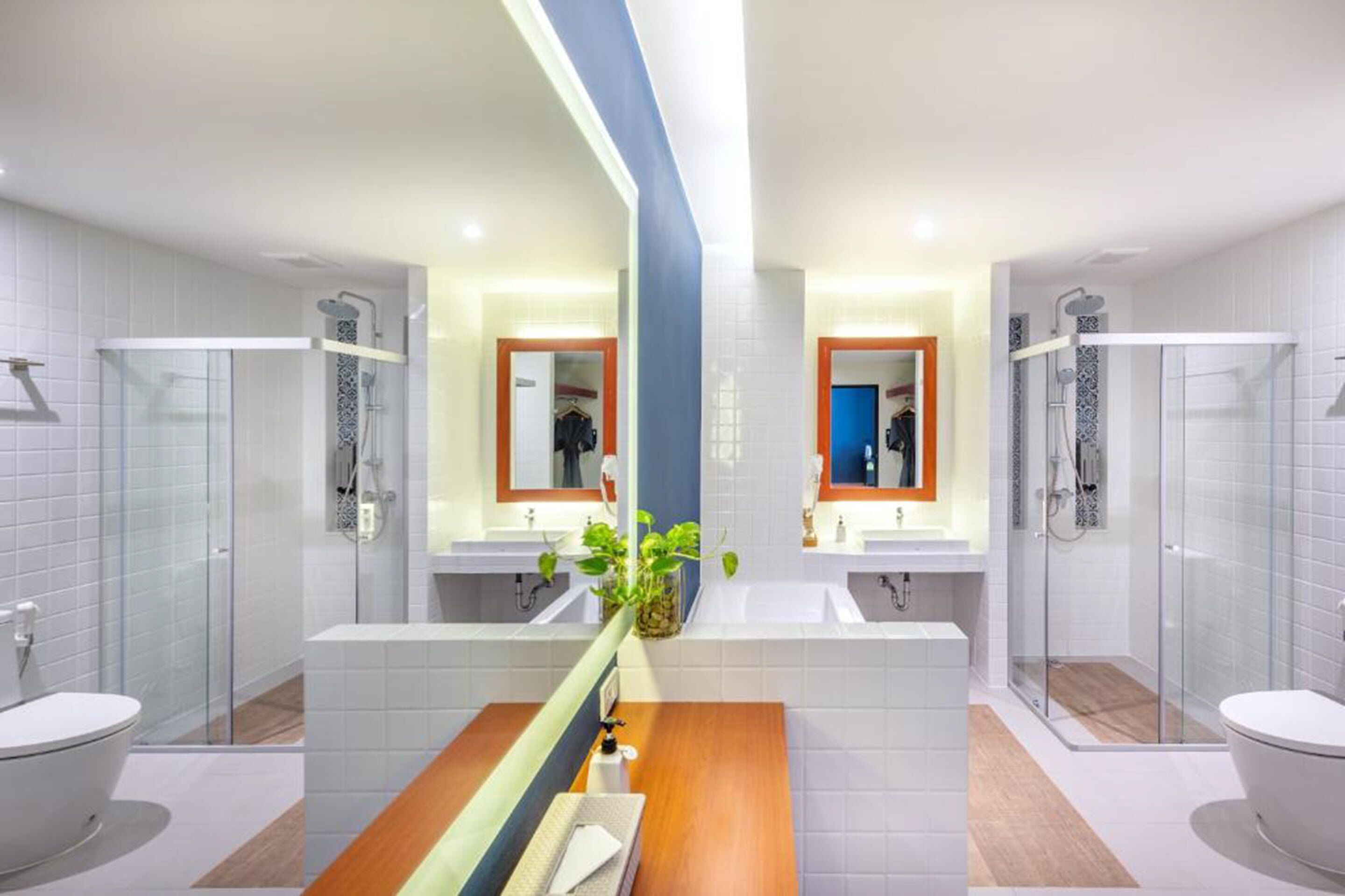 A modern bathroom with two sinks, a wooden vanity, and glass-enclosed showers.