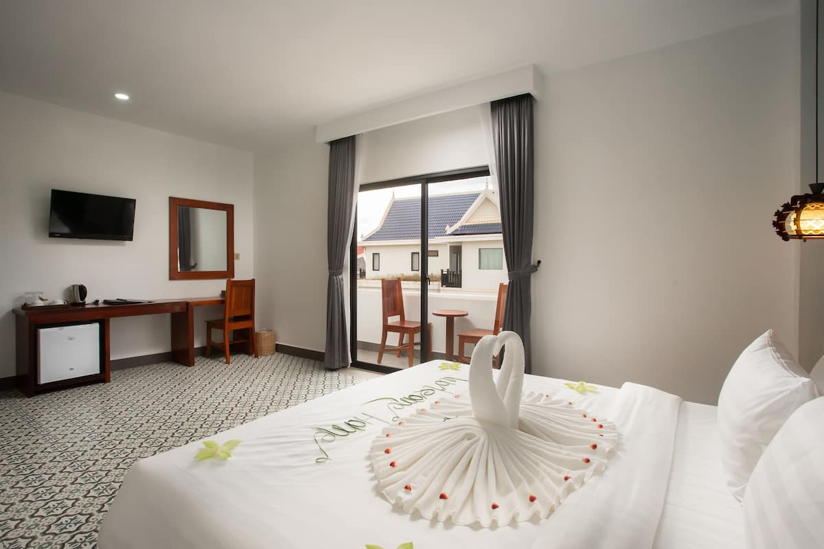 Een hotelkamer met een bed, een bureau, een stoel, een televisie en uitzicht.