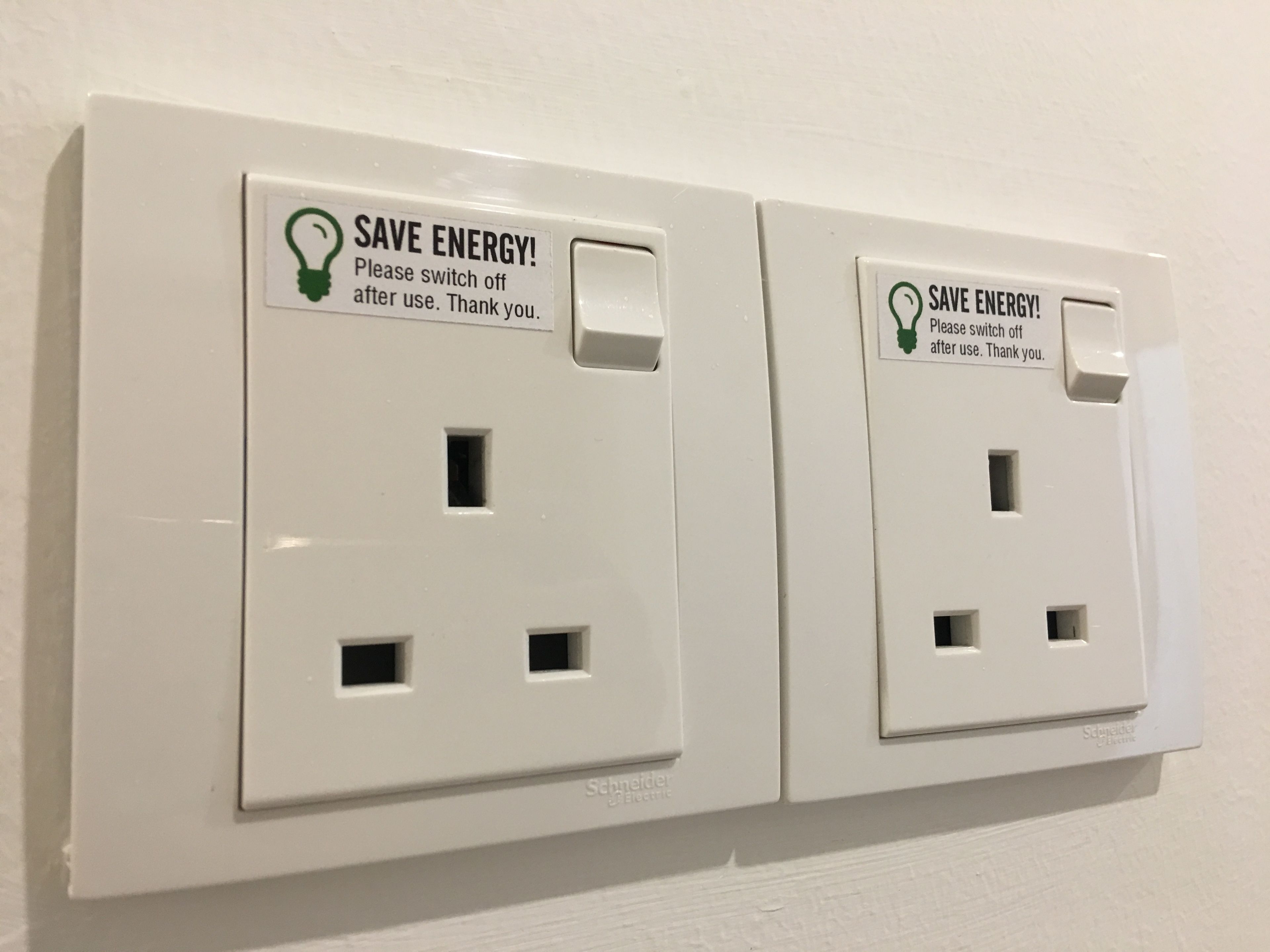Two wall-mounted electrical outlets with 'SAVE ENERGY!' signs and a light bulb icon.