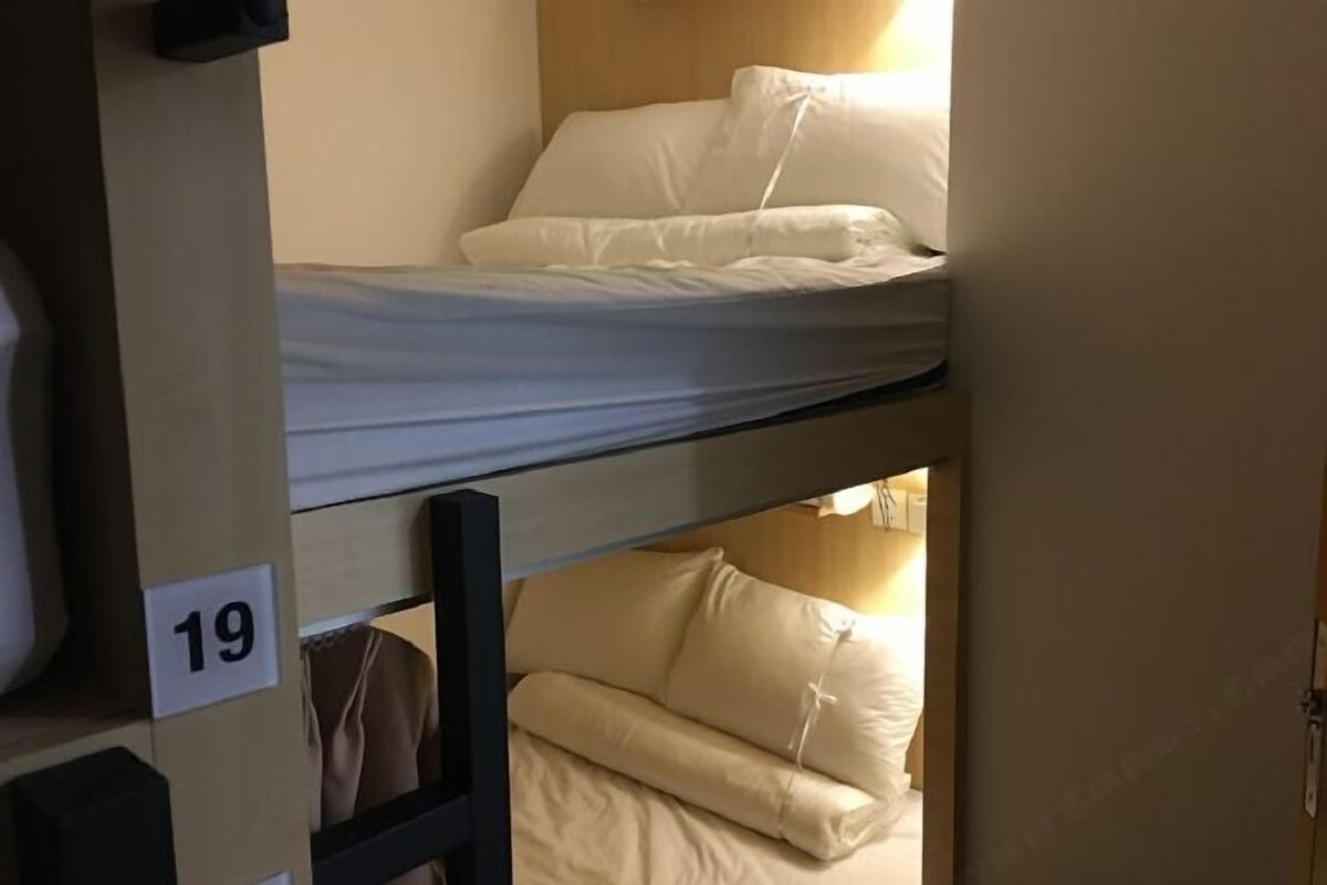 A bunk bed with white bedding and a number '19' sign on the wall.