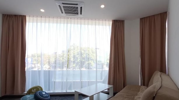 Ein Wohnzimmer mit einem beigefarbenen Sofa, einem weißen Couchtisch und einem blauen Teppich. Auf dem Teppich liegen drei Gymnastikbälle.