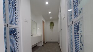 Ein Flur mit einem weißen Waschbecken, einem Spiegel und einer hängenden Pflanze.