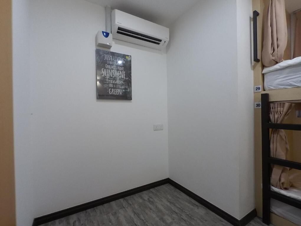 A small, clean room with a bunk bed, a wall-mounted air conditioner, and a motivational quote on the wall.