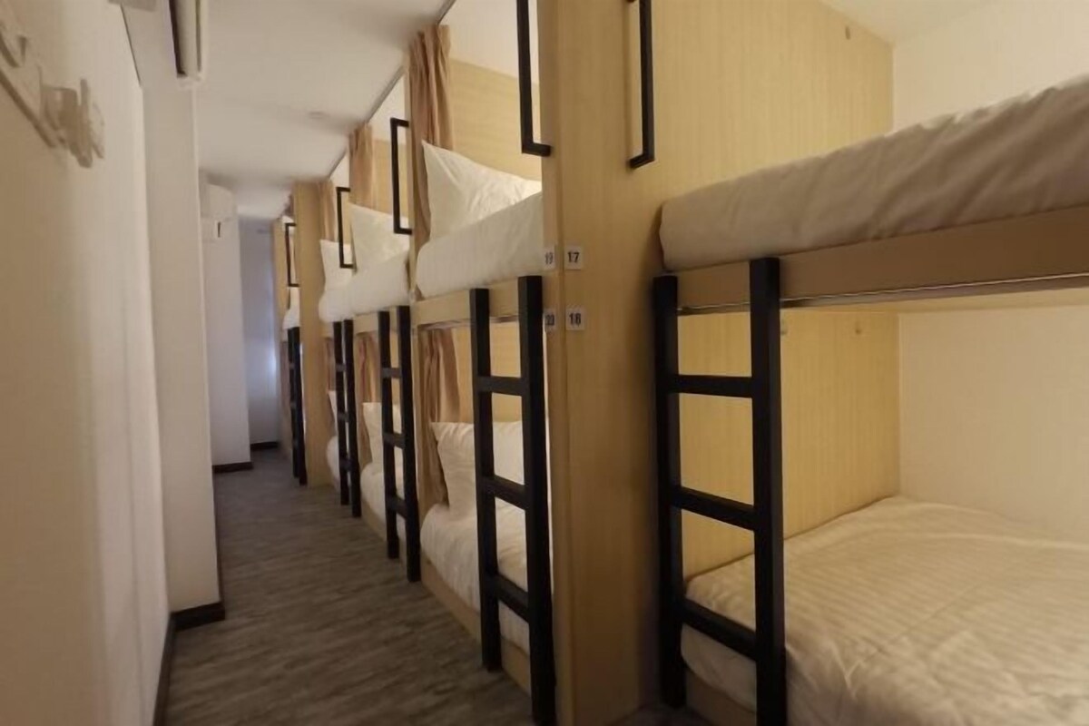 A corridor with bunk beds, wooden headboards, and a carpeted floor.
