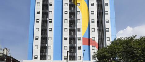 Um edifício com vários andares e fachada azul e amarela marcante, com um grande elemento circular.