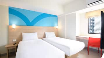 A hotel room with two beds, a desk, a chair, and a large window.