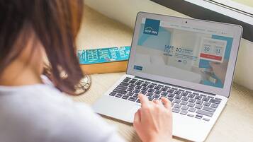 A laptop displaying a hotel booking website with a 'Safe Stay' promotion.