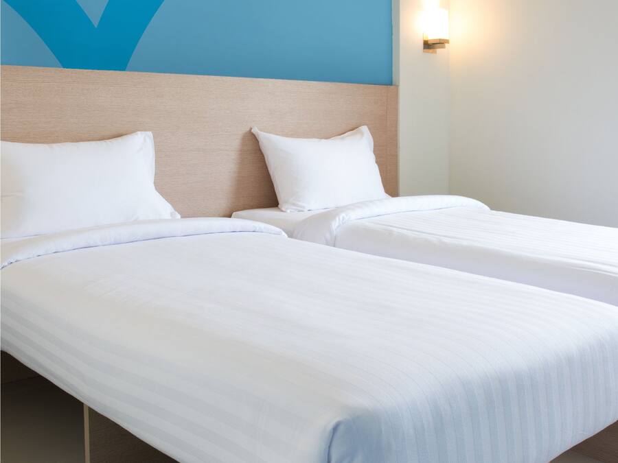 Ein Hotelzimmer mit zwei Betten, einem blauen Koffer und einer Wand mit einem blauen, abstrakten Design.