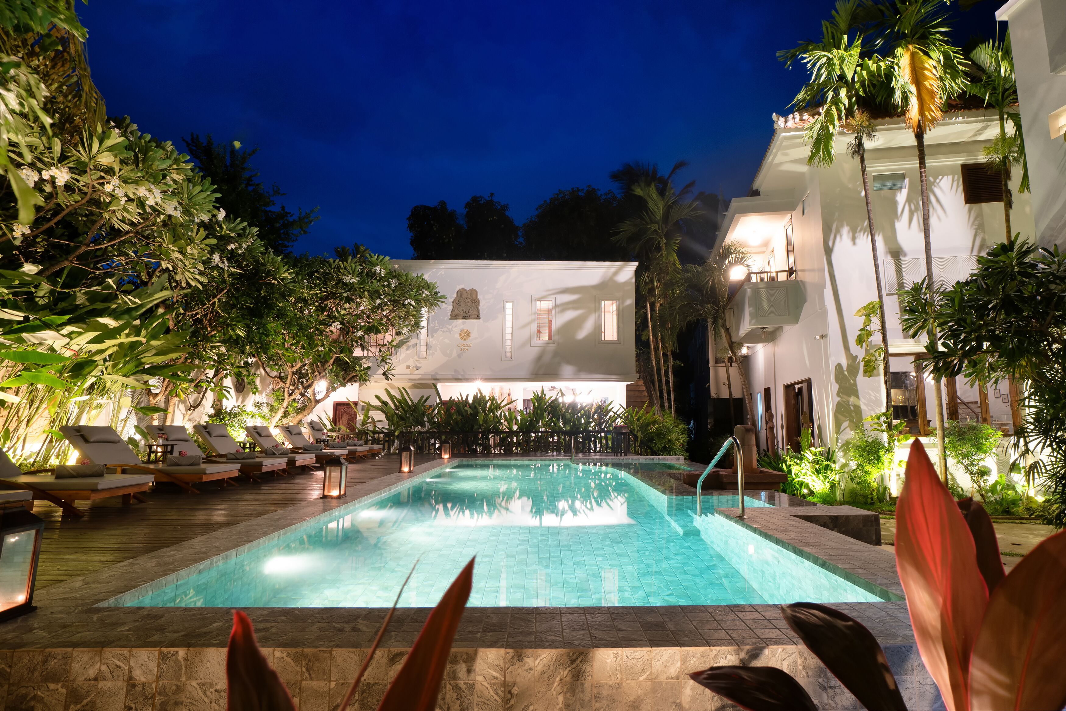 Una piscina al aire libre, sombrillas, sillones reclinables de piscina