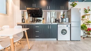 Una cocina moderna con armarios oscuros, horno empotrado, lavadora y refrigerador.