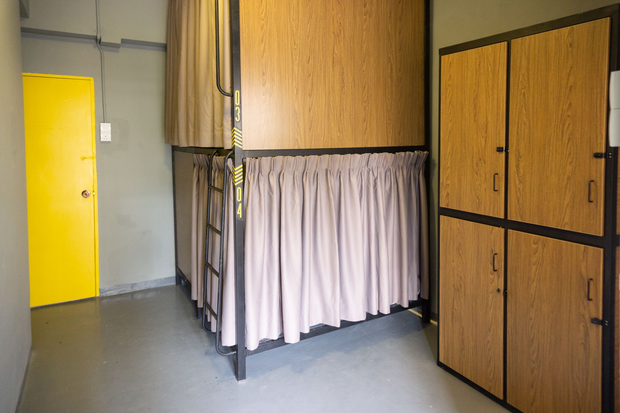 A room with a bunk bed, a yellow door, and wooden wardrobes.