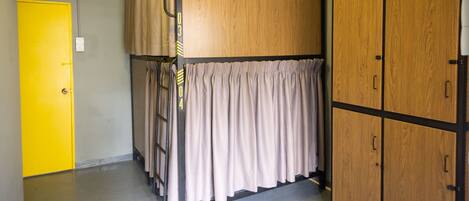 A room with a bunk bed, a yellow door, and wooden wardrobes.