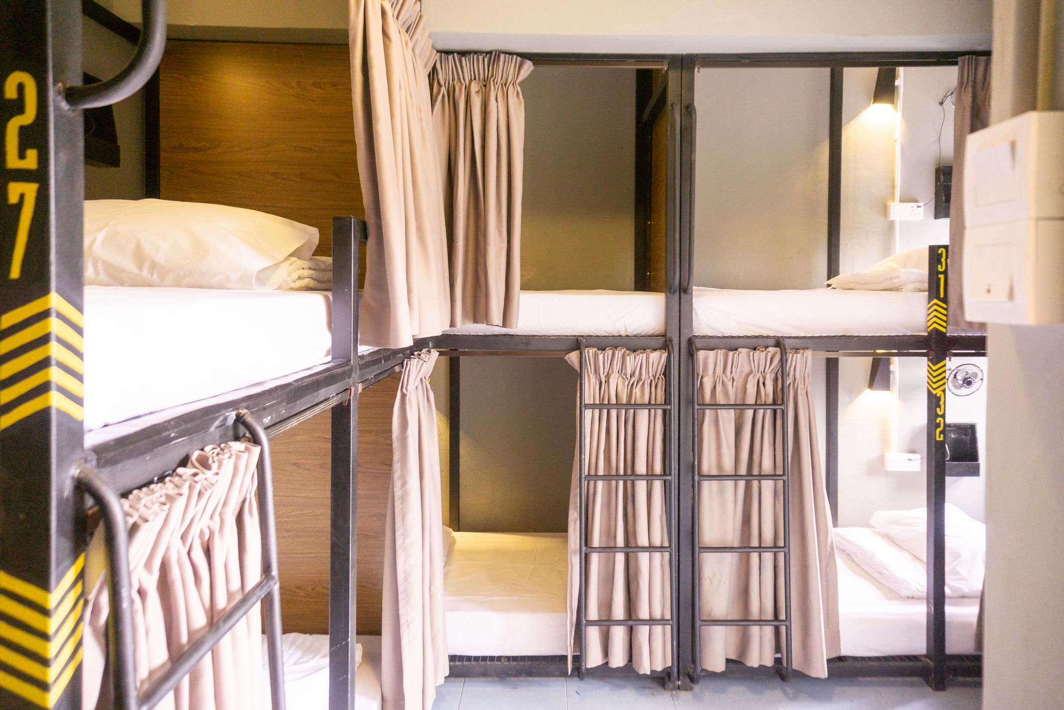 Une chambre avec un lit superposé, des rideaux, une échelle et un panneau indiquant le numéro 27.