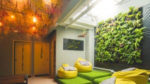 A modern interior with a green wall, yellow bean bags, and a bench.