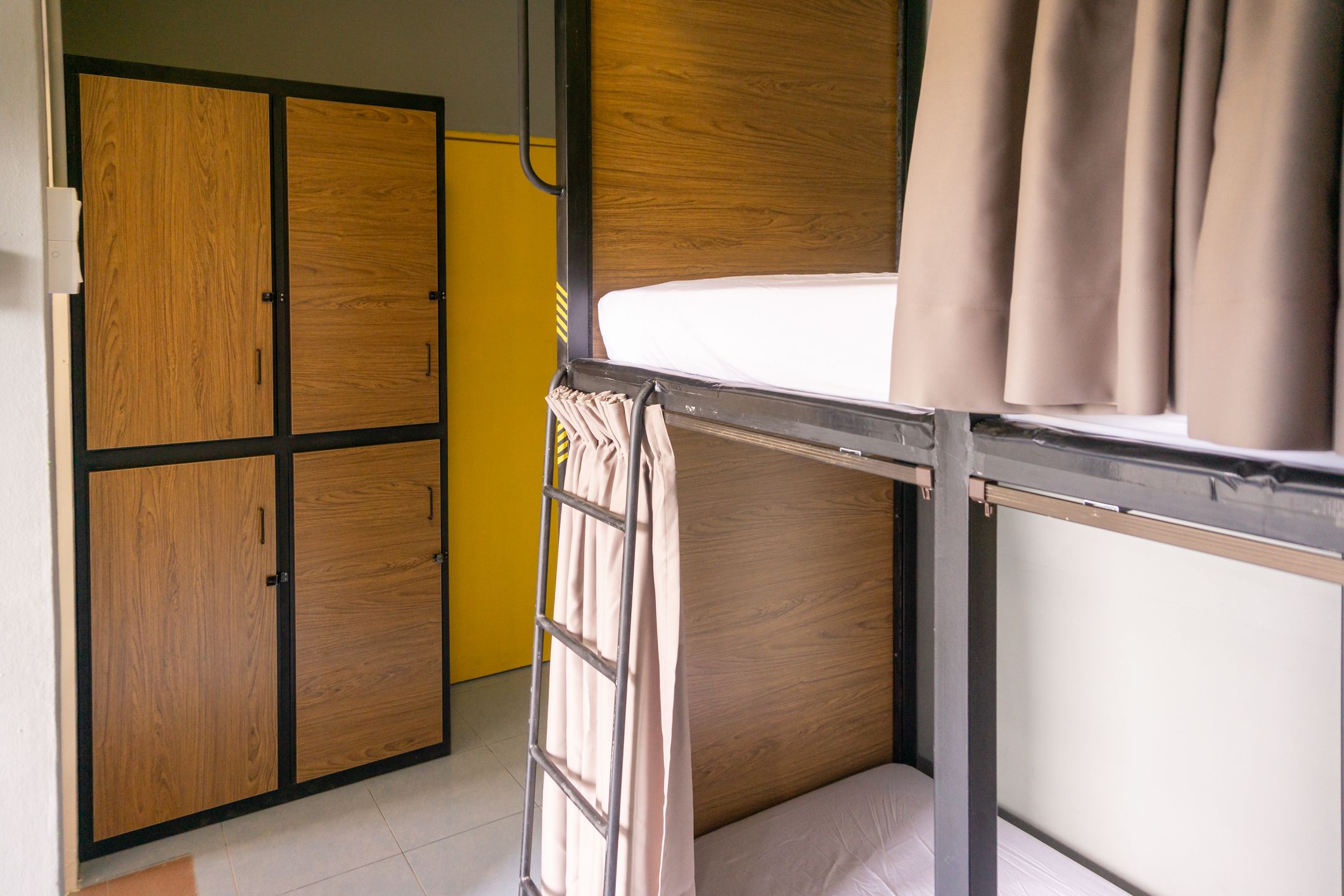 A bunk bed with a wooden headboard, a wardrobe with two doors, and a curtain.