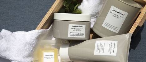A wooden tray with a body cream, a candle, and a bottle of lotion.