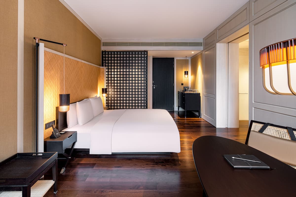 Une chambre d’hôtel moderne dotée d’un grand lit, de tables de chevet, d’un bureau et d’un coin salon.