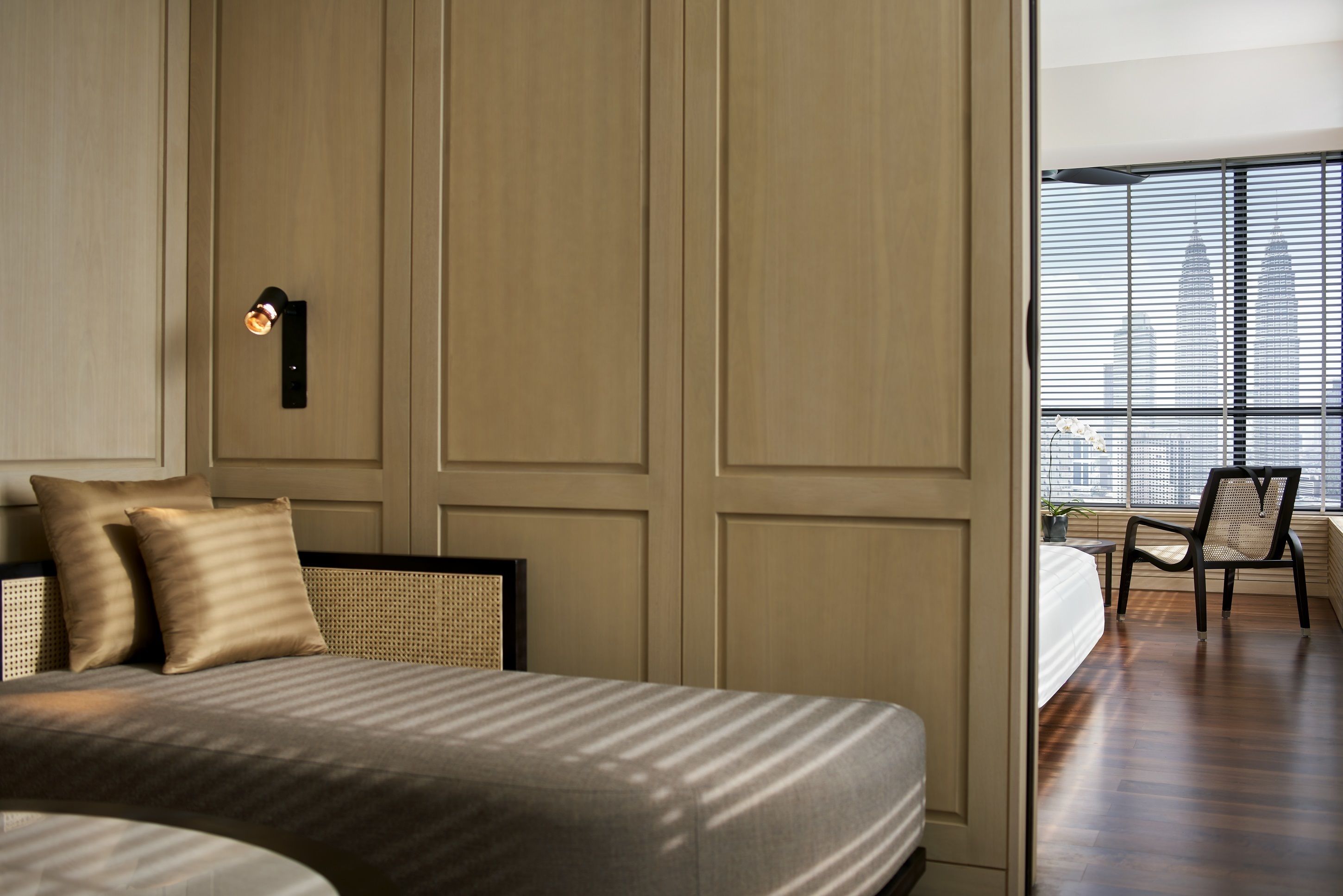 A bedroom with a large bed, a nightstand, a chair, and a view of the city through the window.