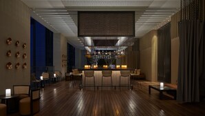 Een moderne bar met een houten vloer, barstoelen en een aanrecht met kaarsen.